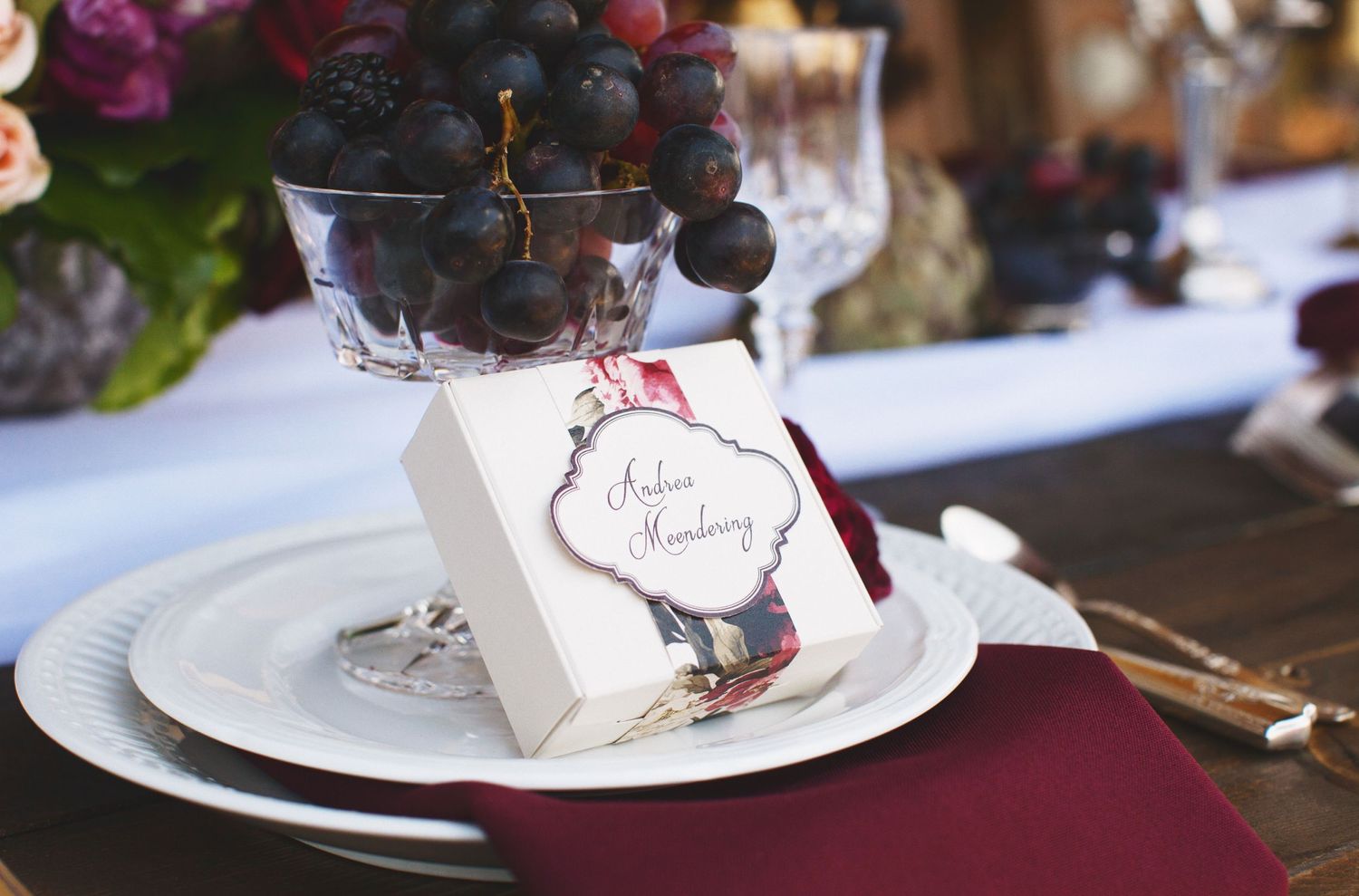table scape with grapes and a favor box on a maroon napkin