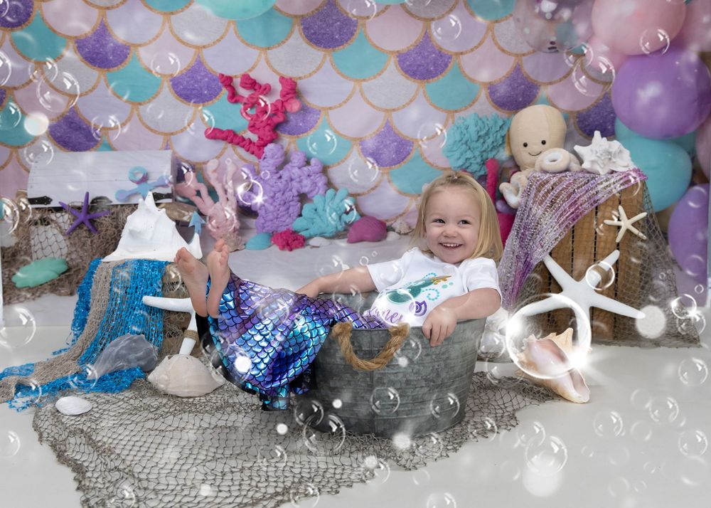 Balloons and decorative elements in purple and turquoise create a festive party atmosphere against a gray backdrop.