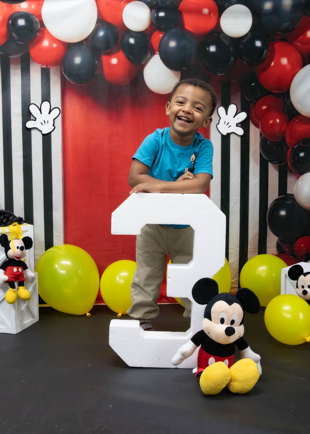 Mickey Mouse themed birthday party setup with balloons, black and white stripes, and a large number 2 decoration.