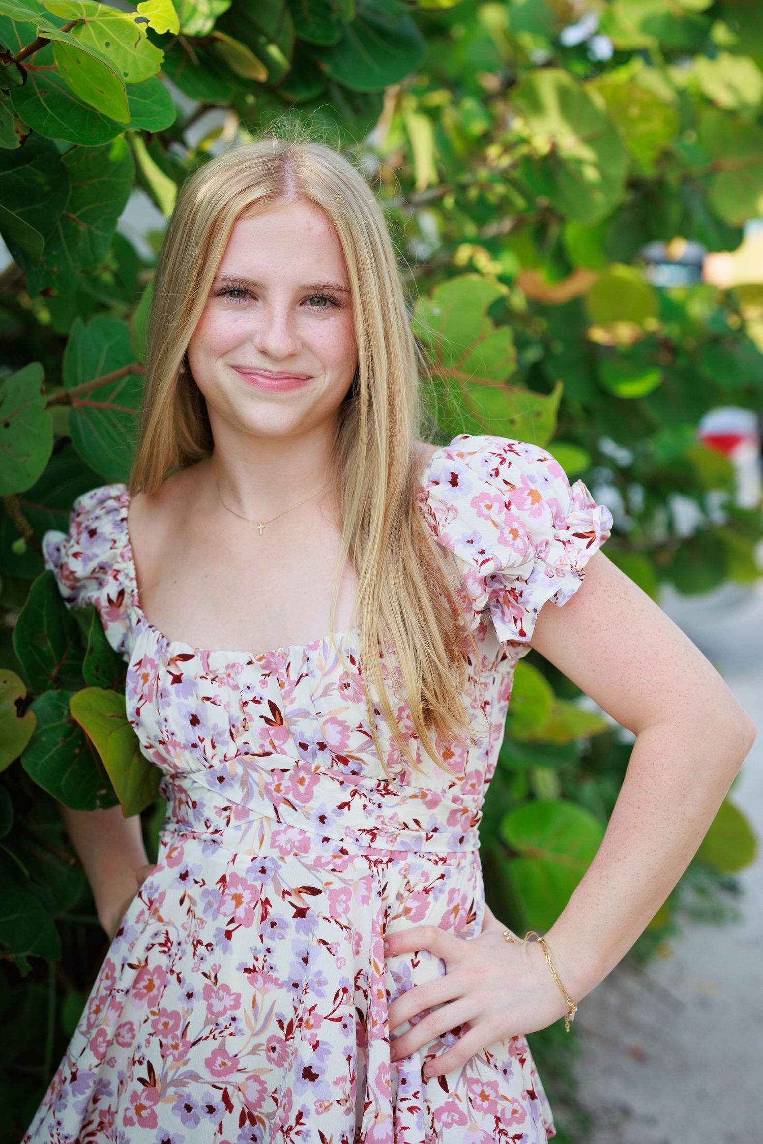Summer portrait in floral dress against leafy green background.