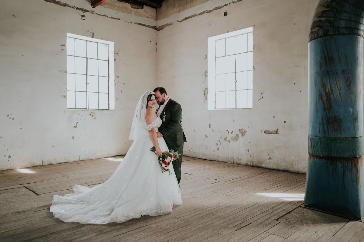A series of four wedding photos showing tender moments in a rustic warehouse setting with white walls and windows.
