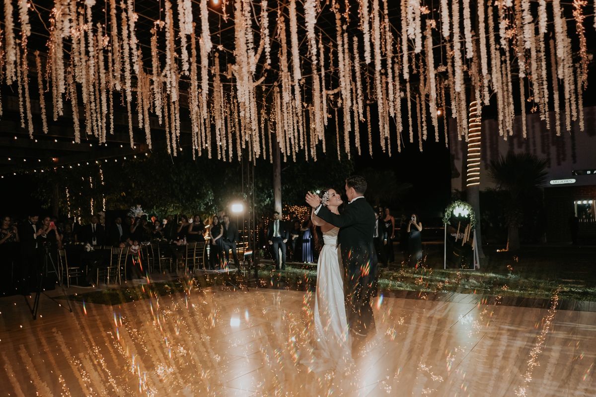 A beautiful outdoor wedding ceremony illuminated by string lights and sparklers creating a magical nighttime atmosphere.