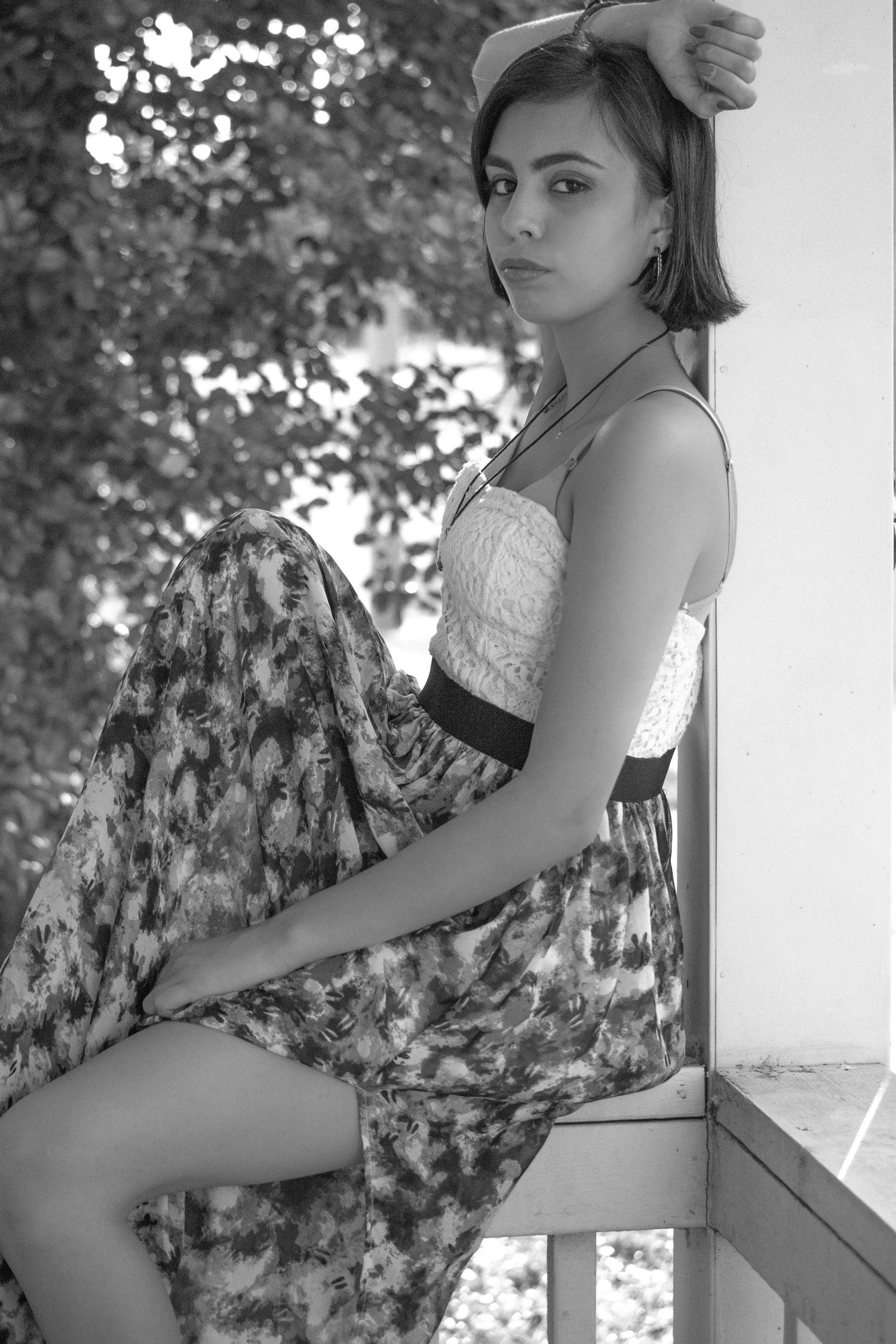 Model in a sun dress sitting on porch