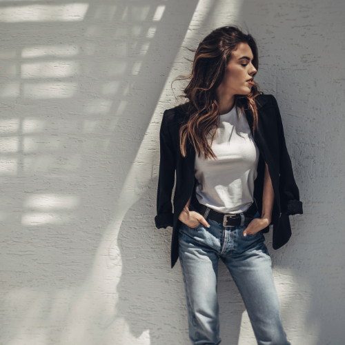 model in jeans and jacket leaning on wall