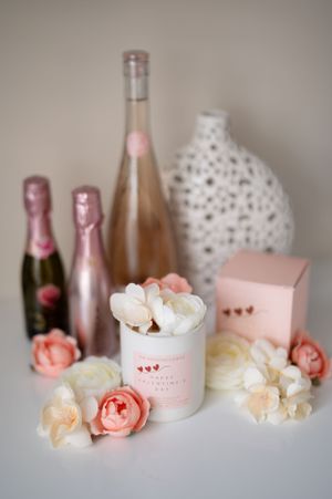 Pink and white roses arranged with rosé wine bottles and decorative vases in a soft, romantic Valentine's Day styled setting.