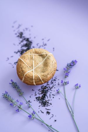 Homemade shortbread cookies with cross pattern decorations arranged with purple lavender sprigs and loose tea leaves.