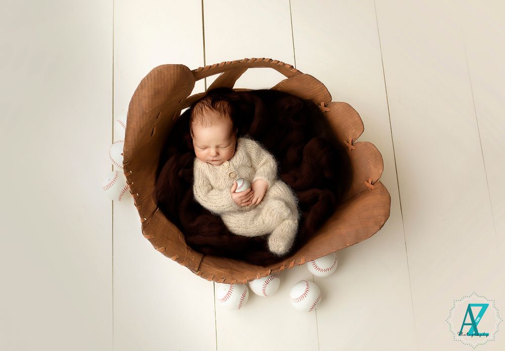 Overhead view of sleeping newborn in white wrap nested in brown flower-shaped prop.