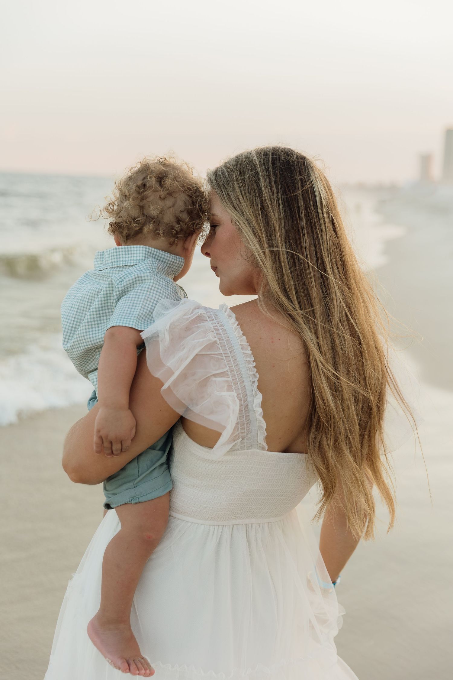 a mother holding her daughter in natural light in an open field