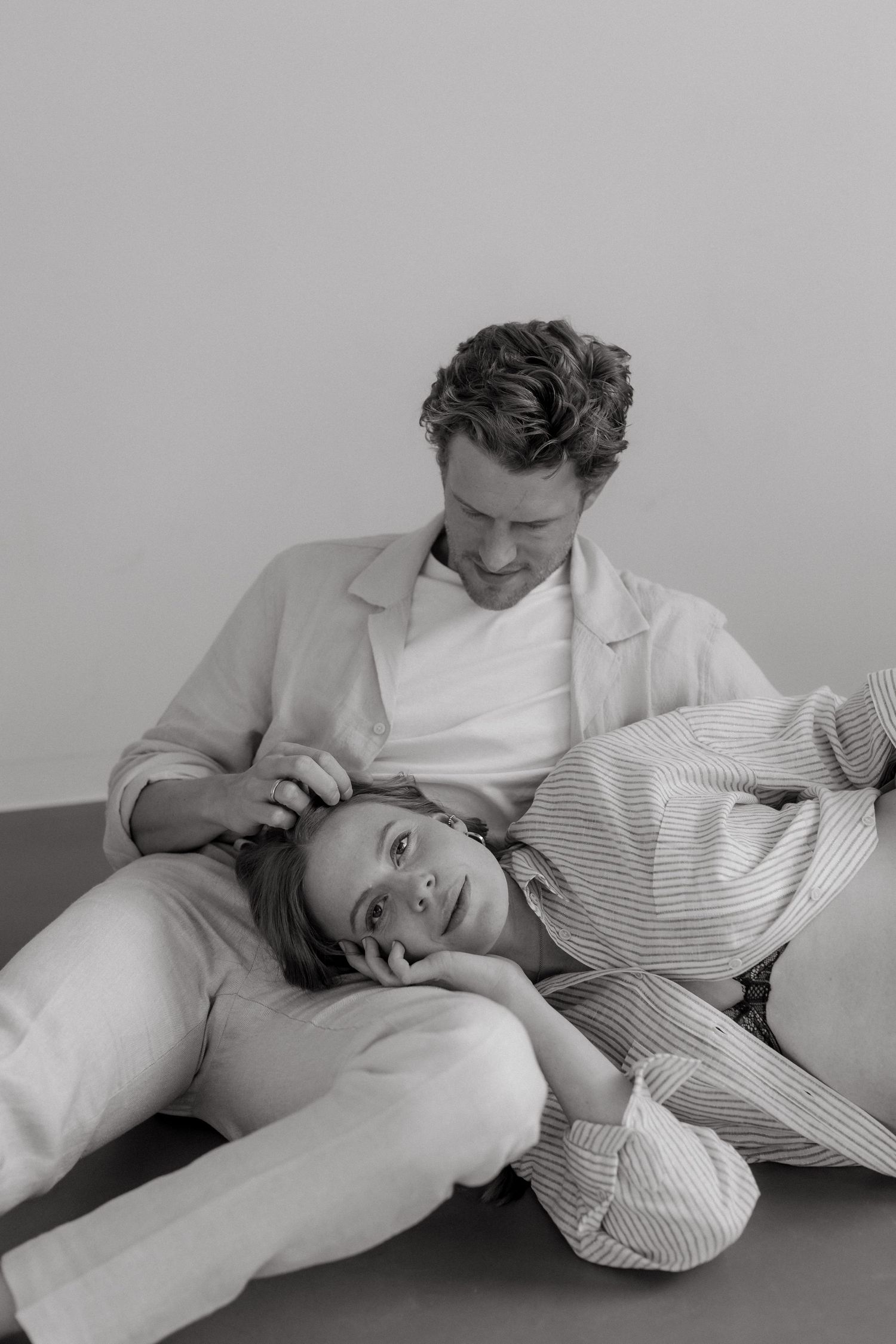 Black and white photo series showing relaxed casual poses on light surface.
