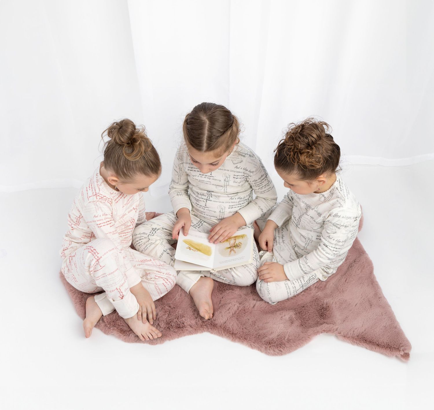 A toddler in a white top and coral skirt examines a decorative starfish on a white background.