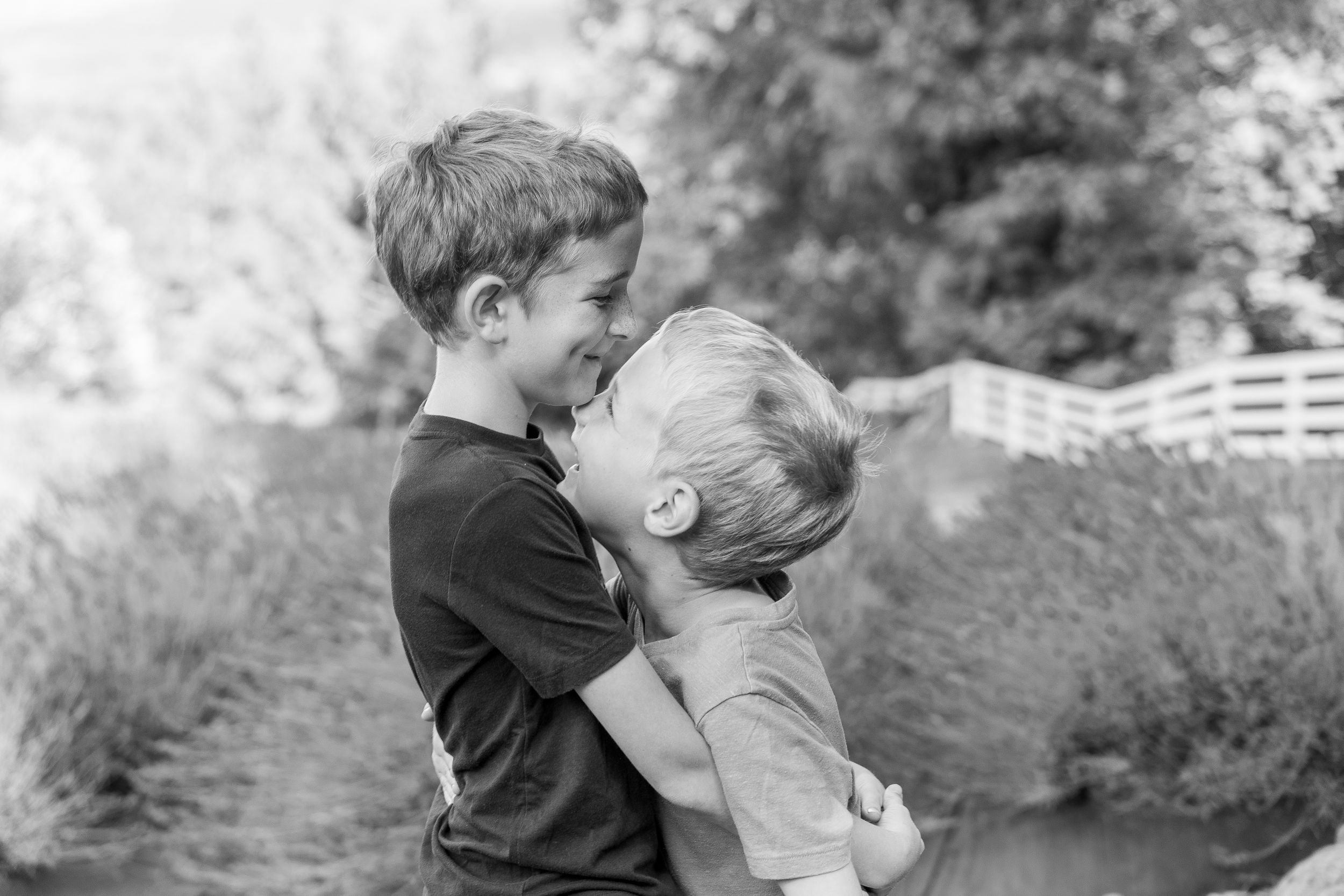 Black and white photo of two young children embracing outdoors.
