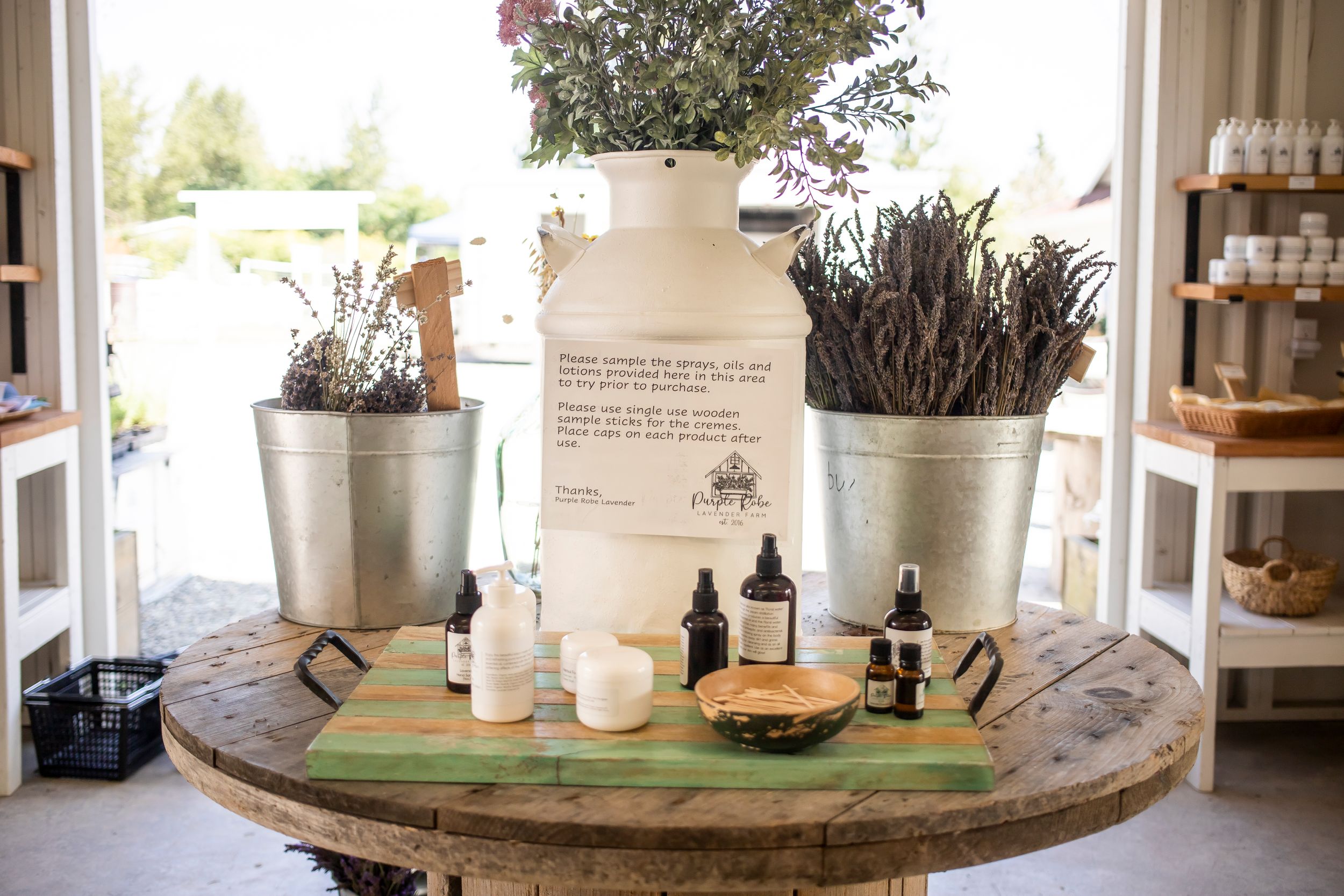 Rustic table display with dried flowers in milk jugs and various decorative items.