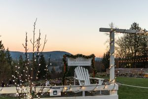 Outdoor seating area with white Adirondack chair and string lights at sunset with mountain views.