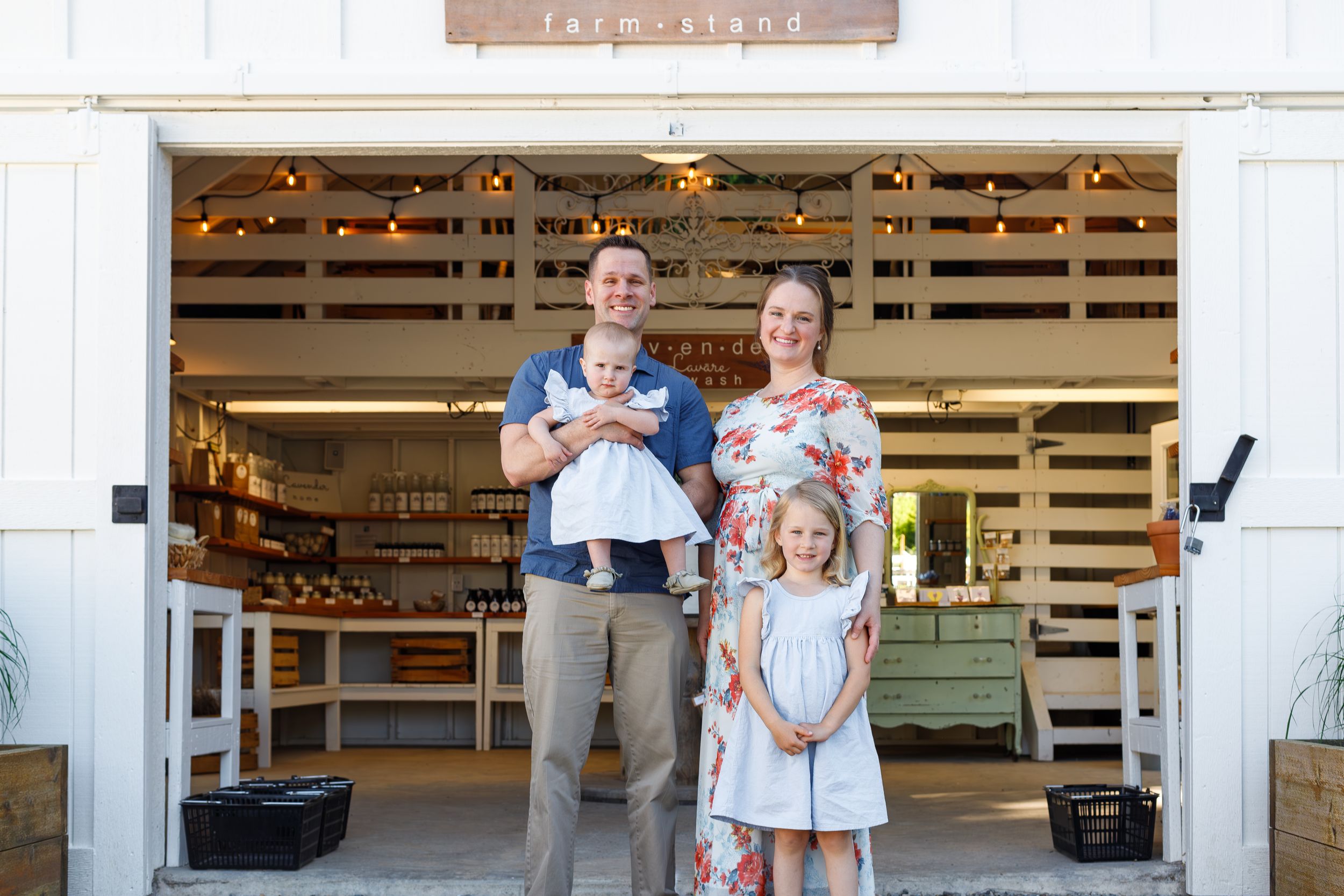 Family standing together outside rustic barn entrance with wooden slat walls.