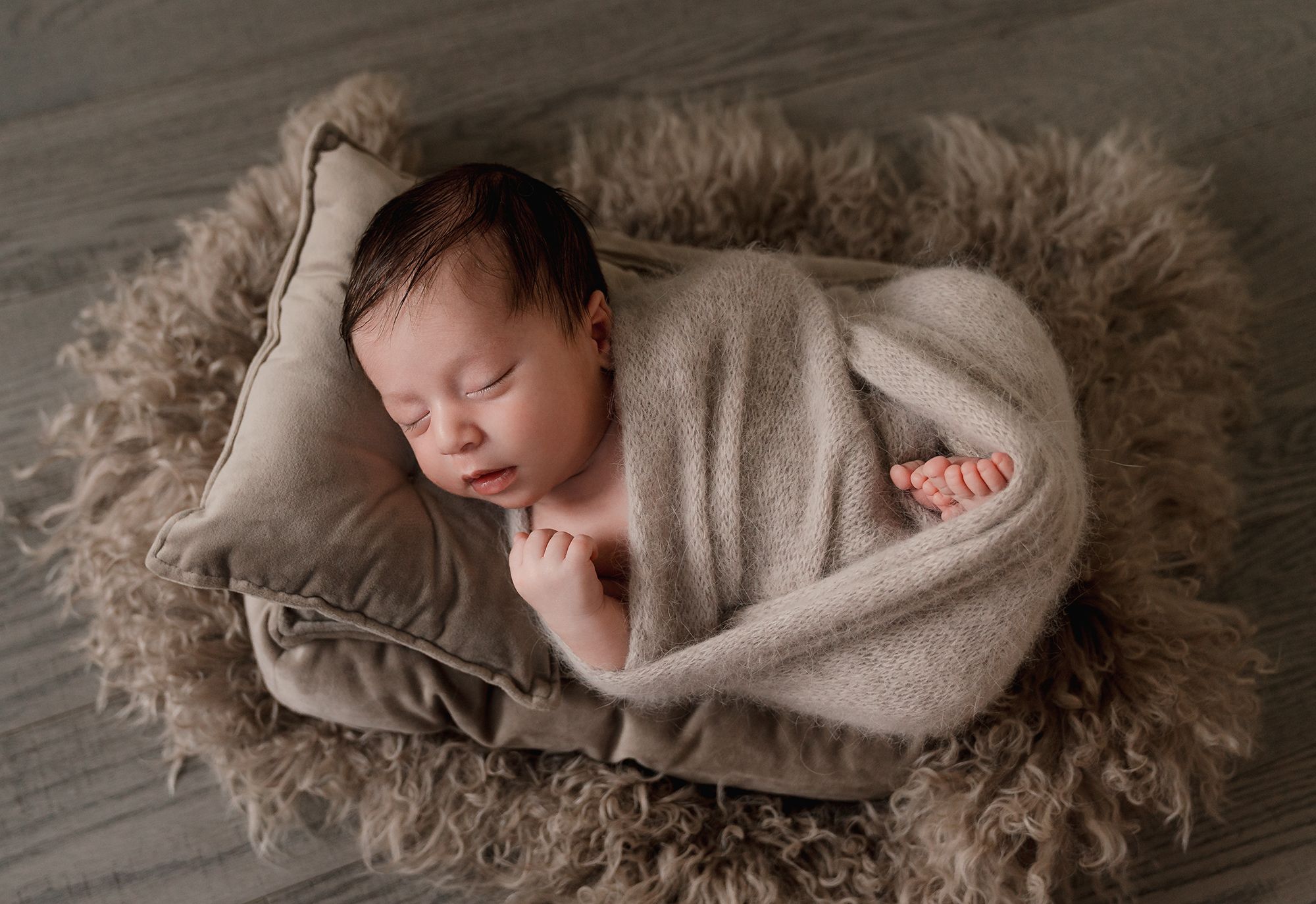 Sleeping newborn baby wrapped in soft beige blanket on textured rug in multiple artistic poses.