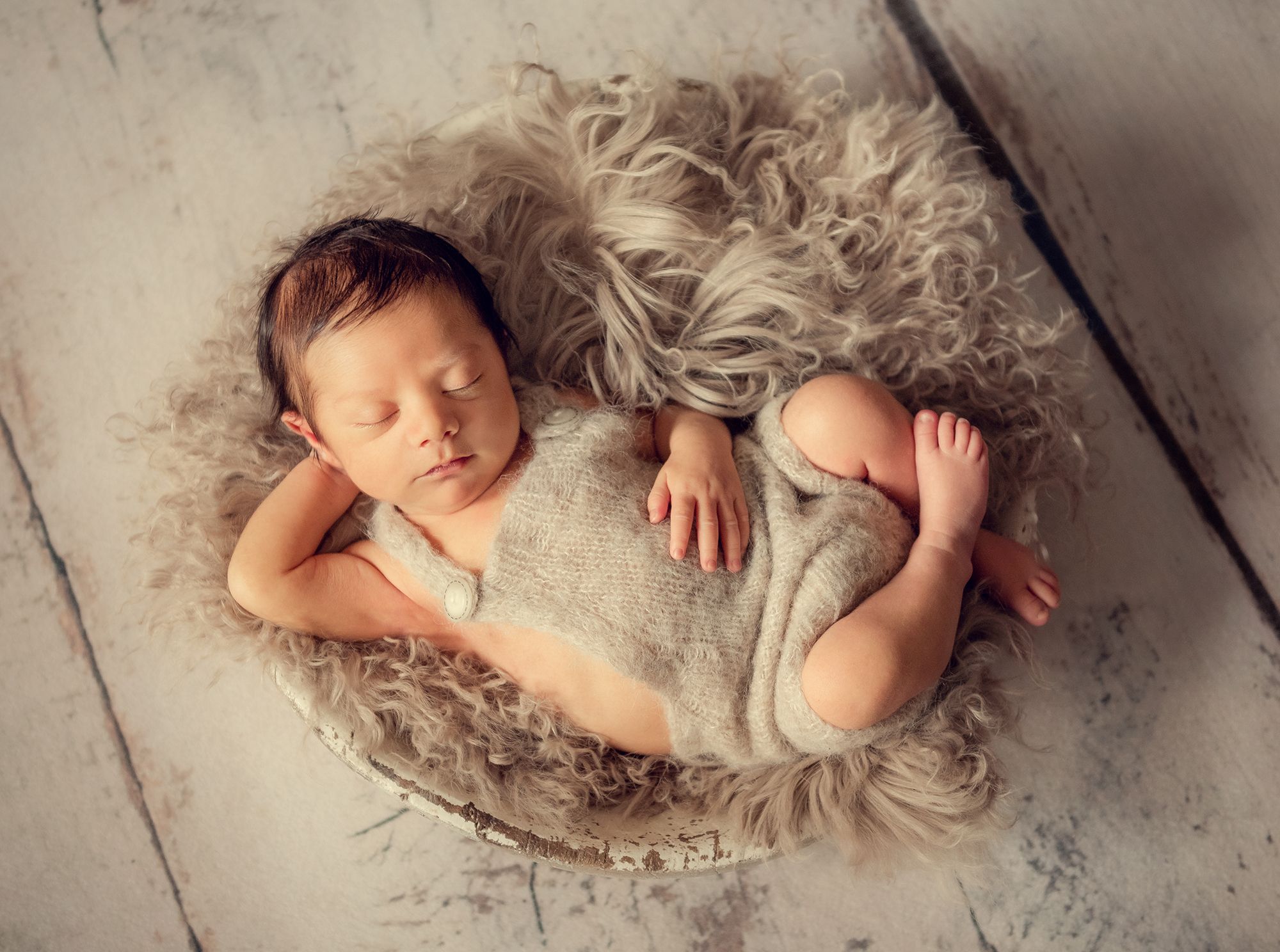 newborn baby is in the resting pose in a bowl prop during the photo session at home using natural light setup