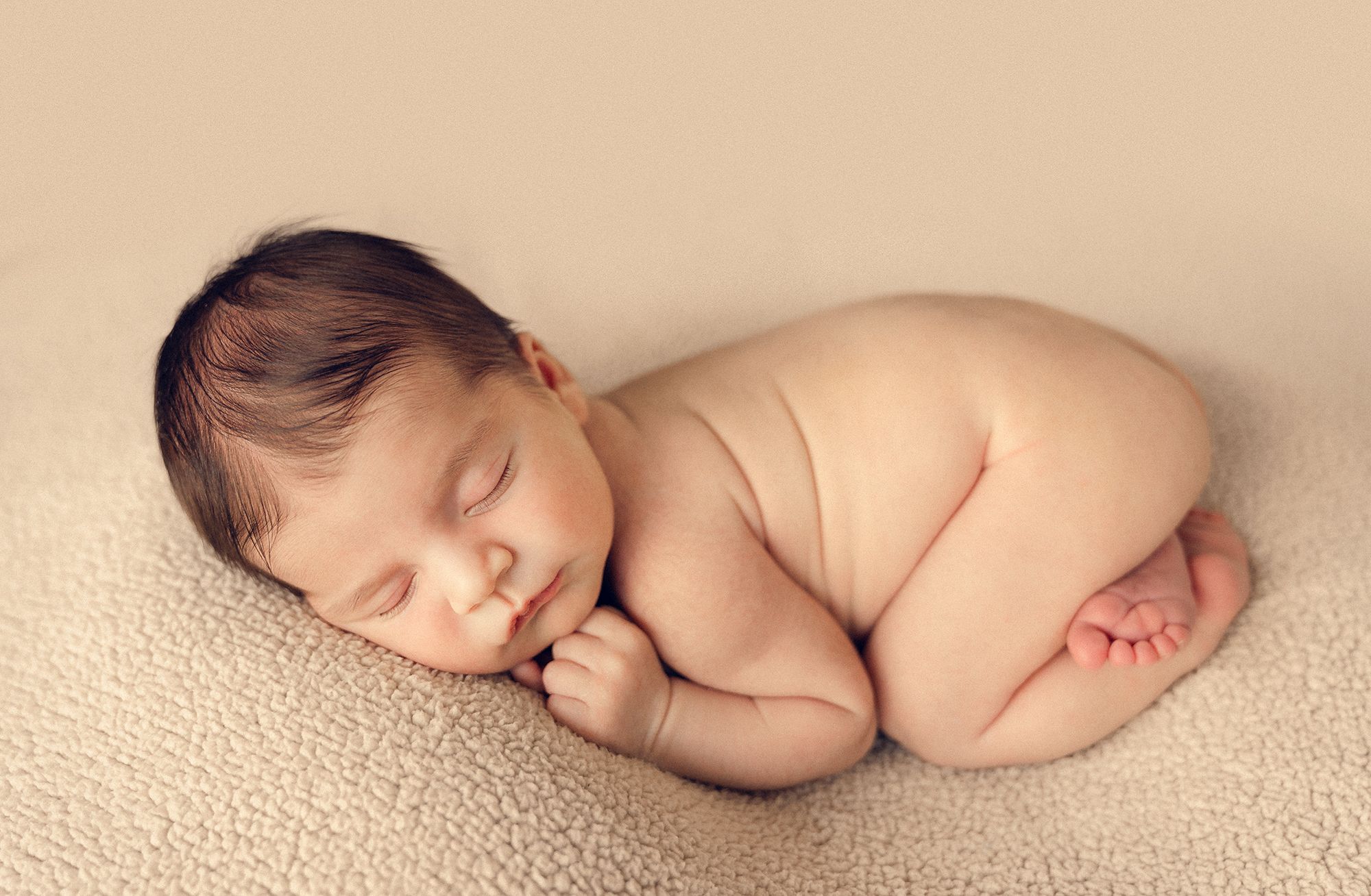 the baby is in the classic newborn pose on a bean bag during a photoshoot in a comfort of a home in Woodbridge, Ontario
