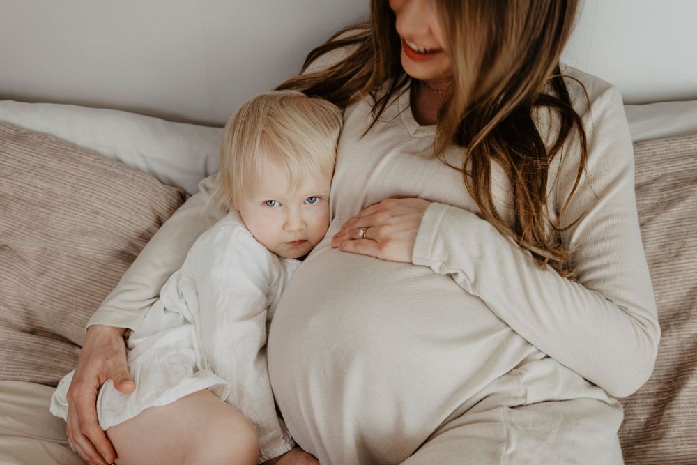Família sorridente reunida na cama, celebrando a chegada de um novo bebê com carinho e ternura.