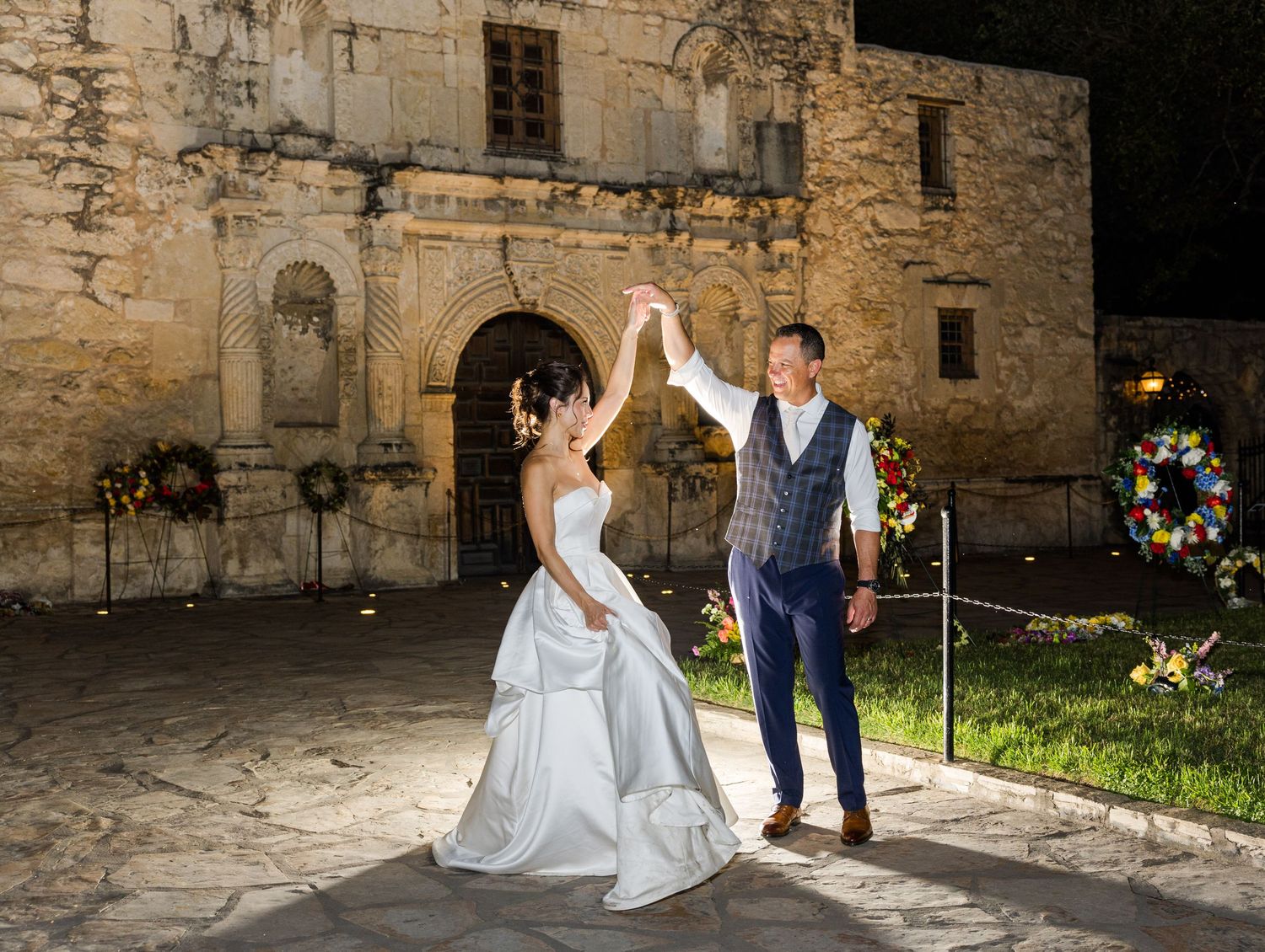 Groom twirls his bride in front of the Alamo in San Antonio, Texas