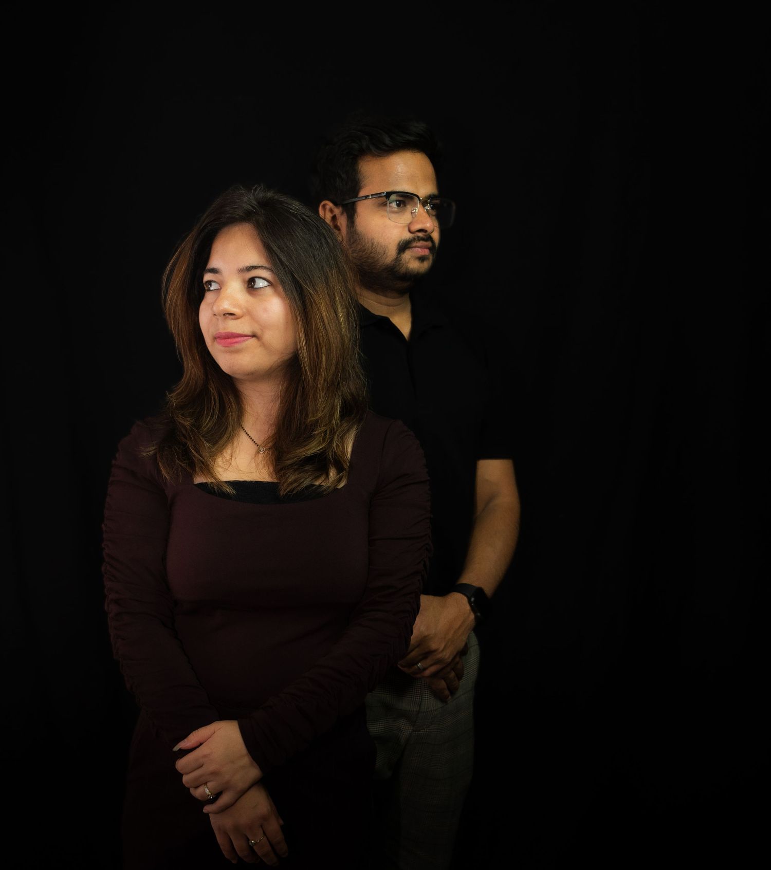 Artistic studio portrait of couple against black background.