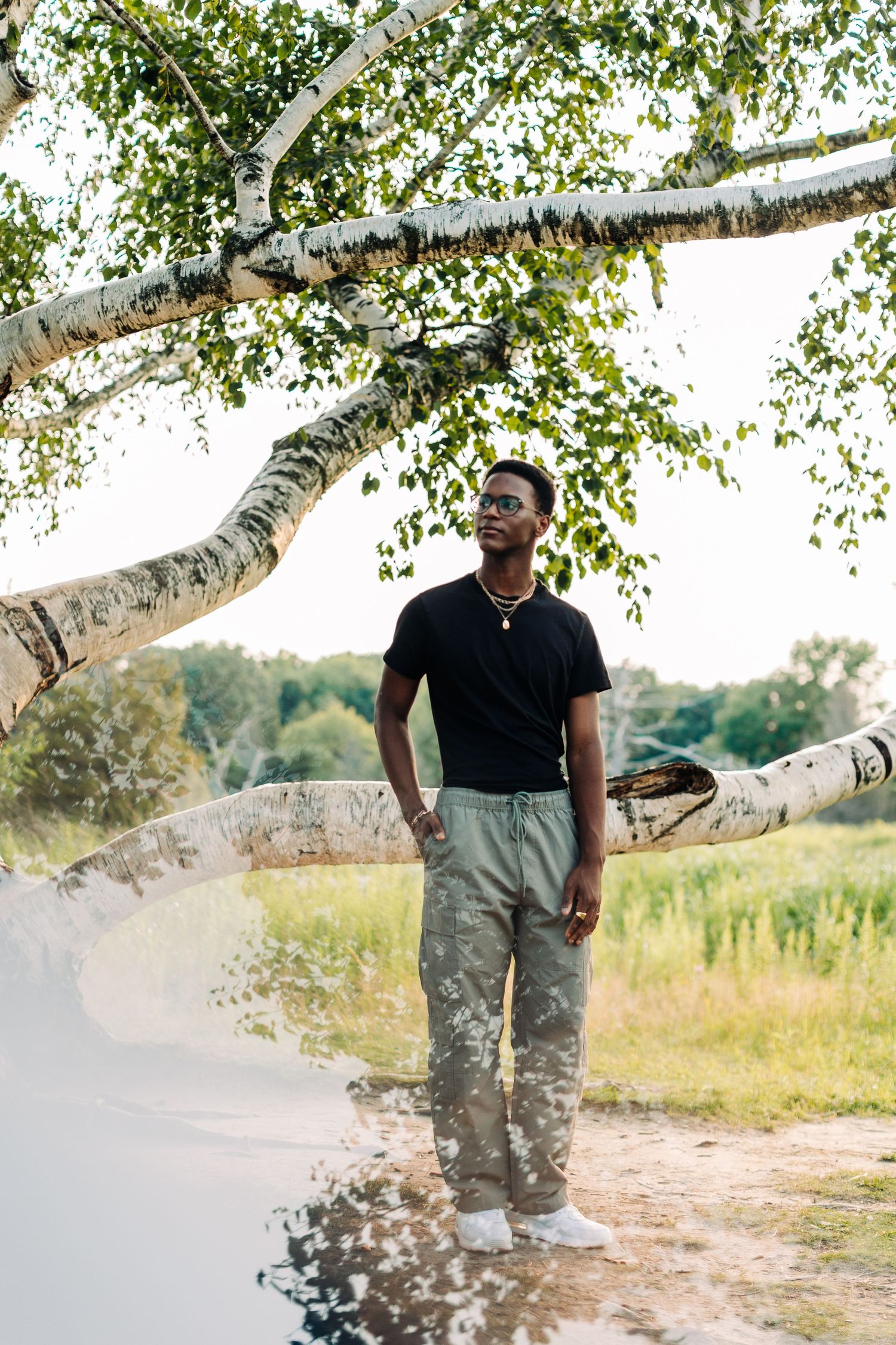 Casual outdoor portrait against a birch tree wearing a black polo and cargo pants.