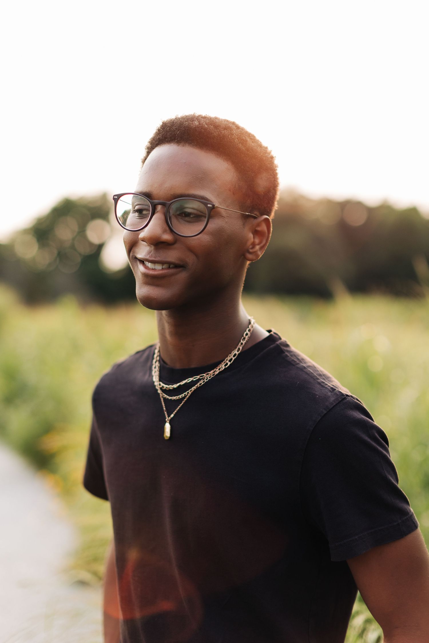 Stylish portrait featuring glasses and jewelry with warm sunset lighting.