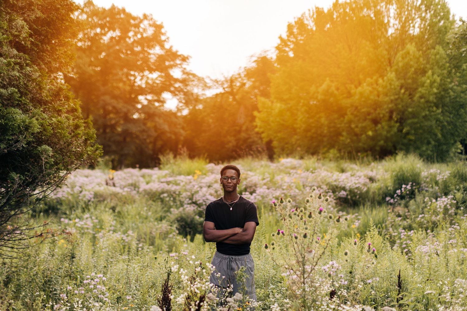 Warm-toned portrait in a nature setting with golden hour lighting and wildflowers.