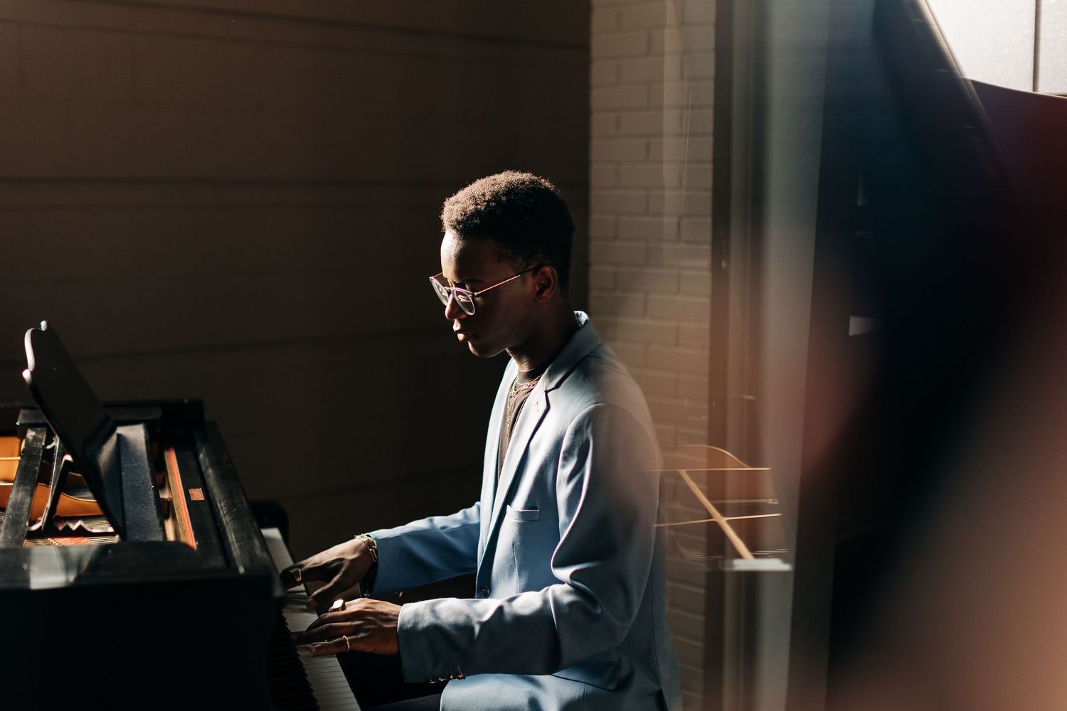 A musician practices at a piano in moody lighting.
