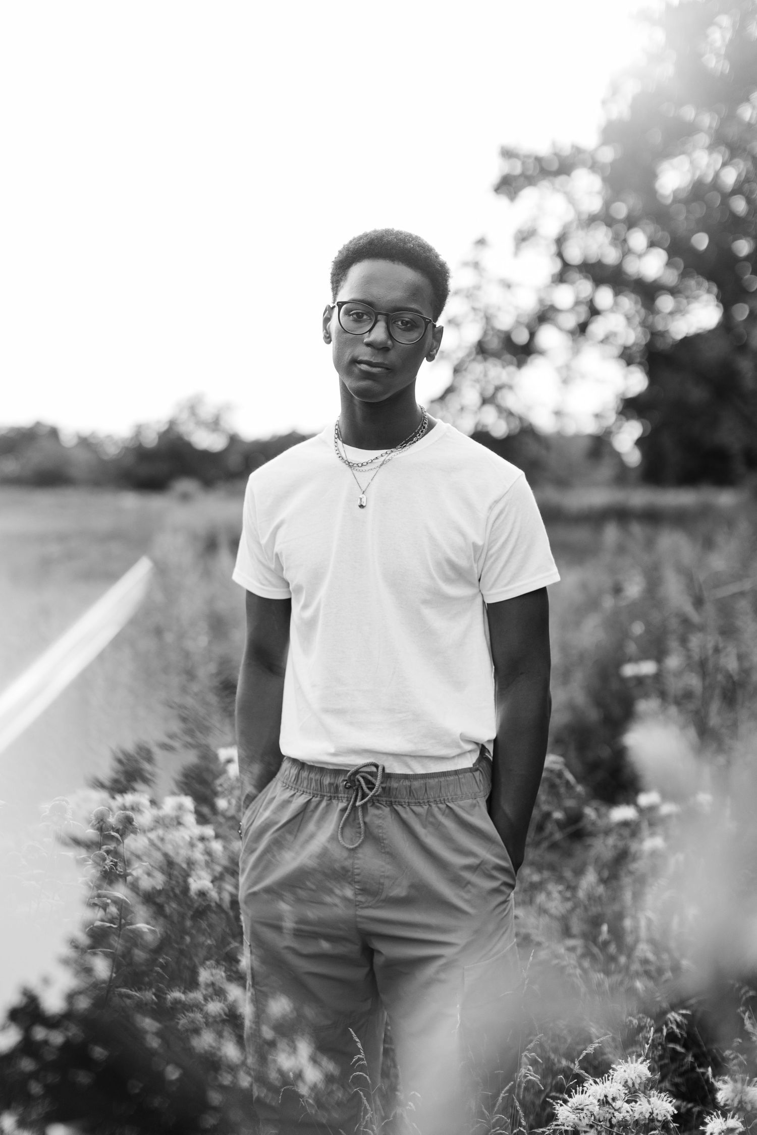 Black and white portrait in natural setting with wildflowers.