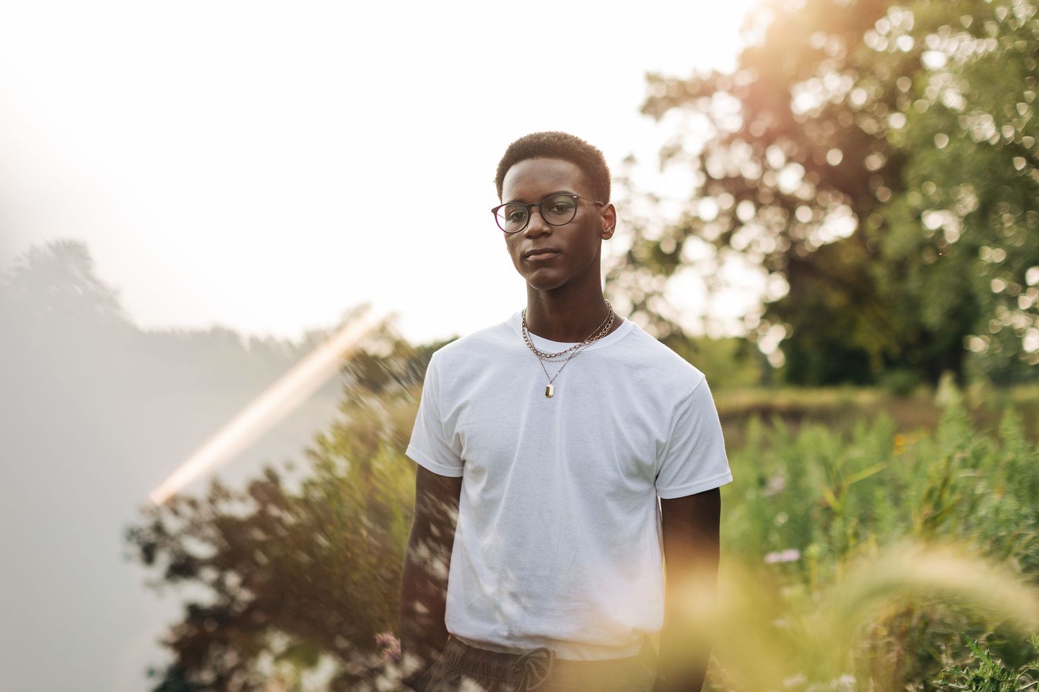 Portrait in soft lighting with bokeh effect through summer foliage.