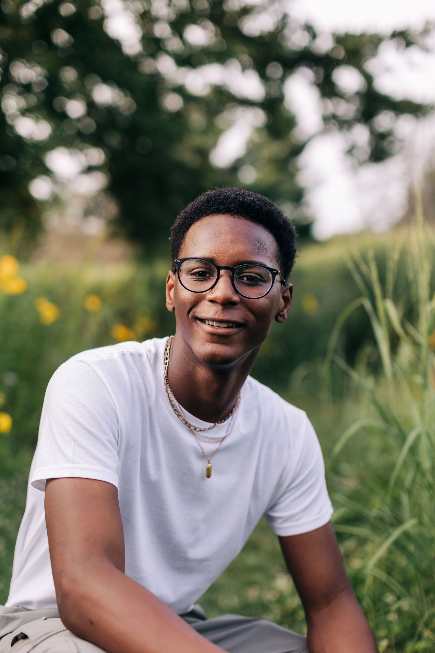Portrait in natural setting with glasses and white t-shirt among summer foliage.