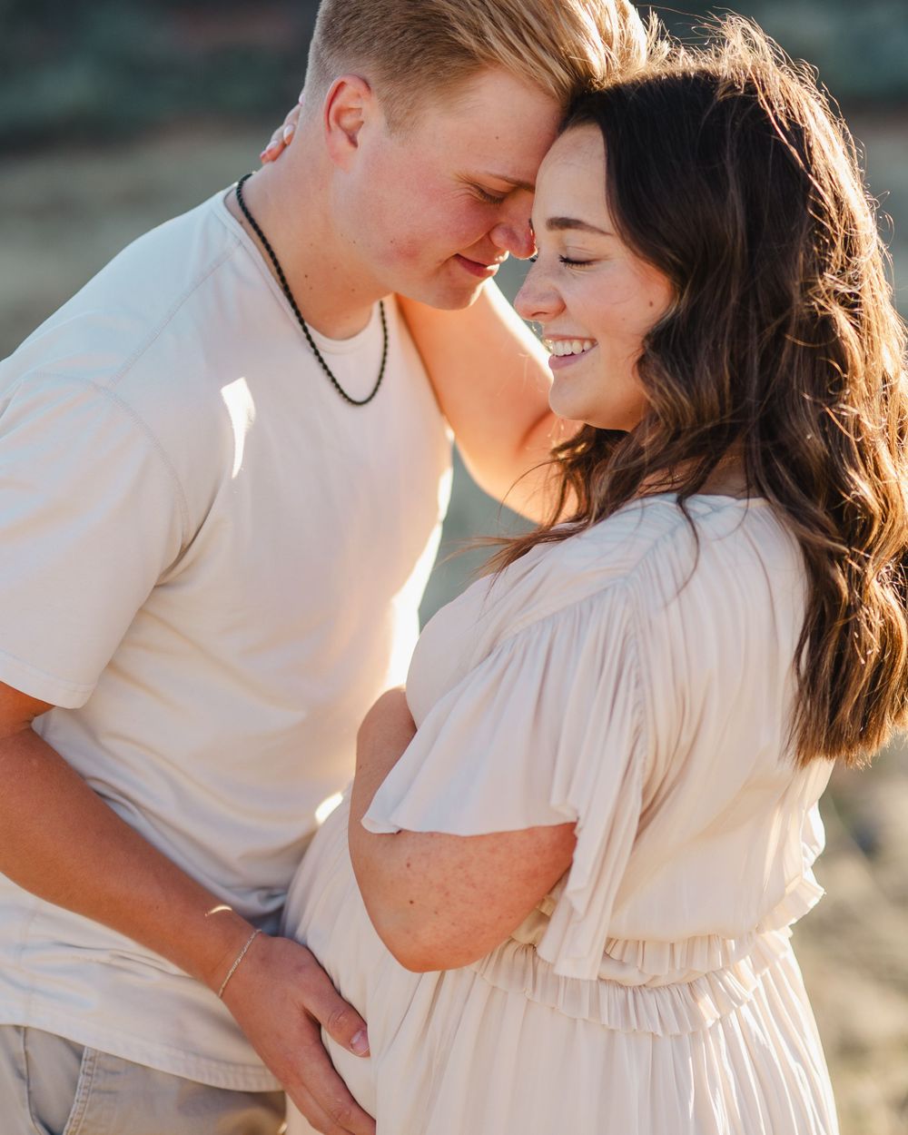 Intimate moment between couple in white clothing against rocky backdrop at golden hour.