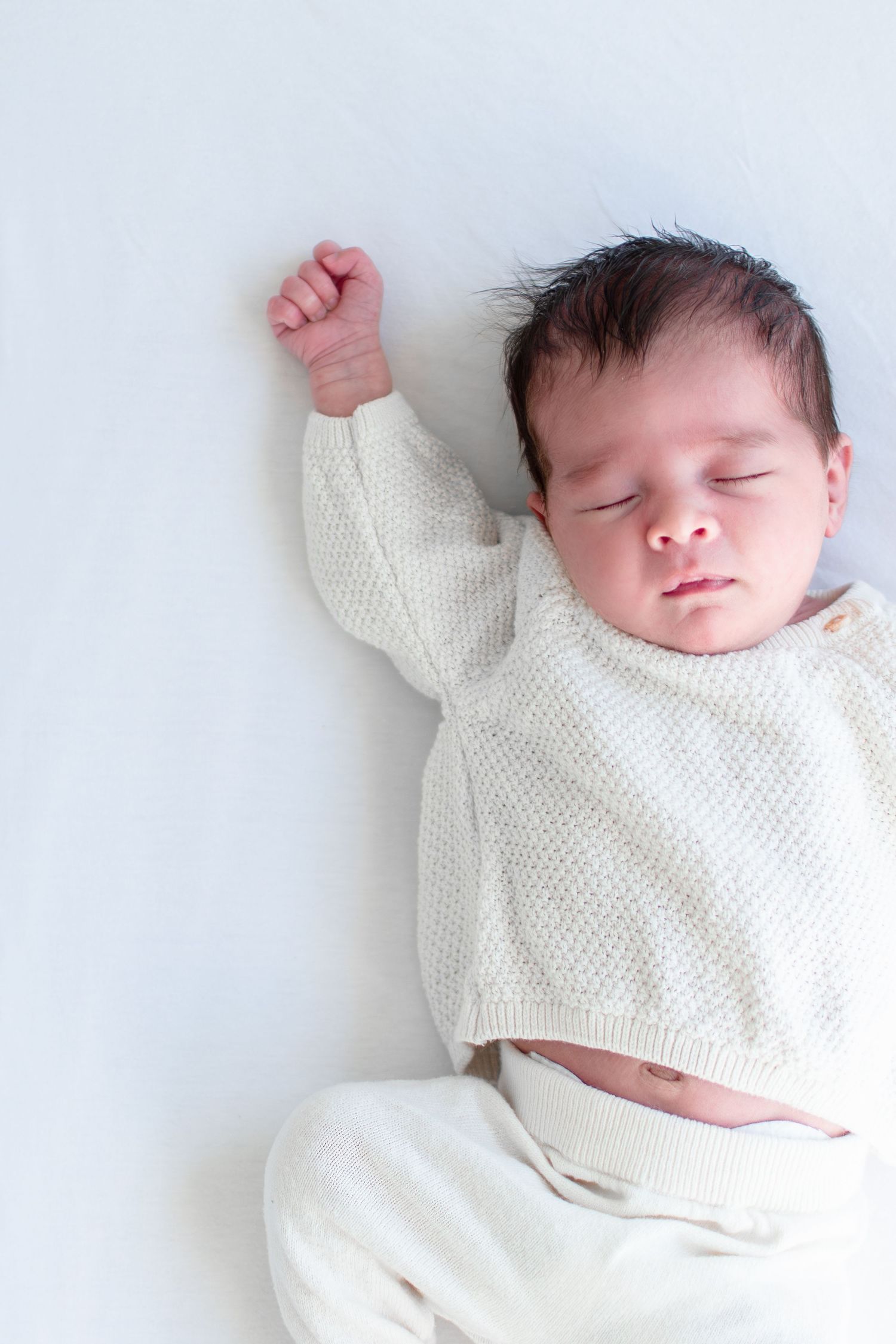 Baby girl stretches in her crib.