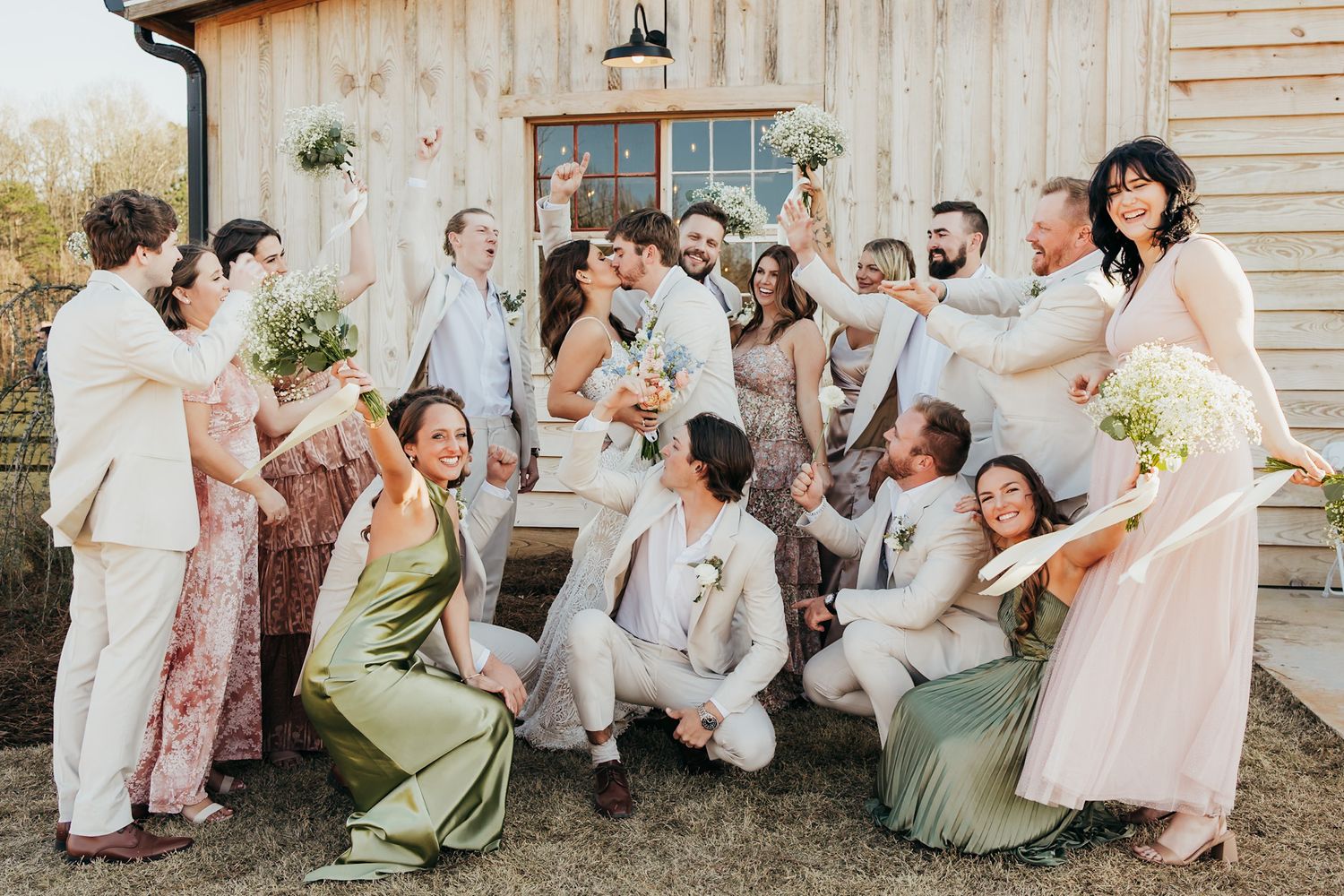 bride and groom kissing with entire bridal party cheering around them