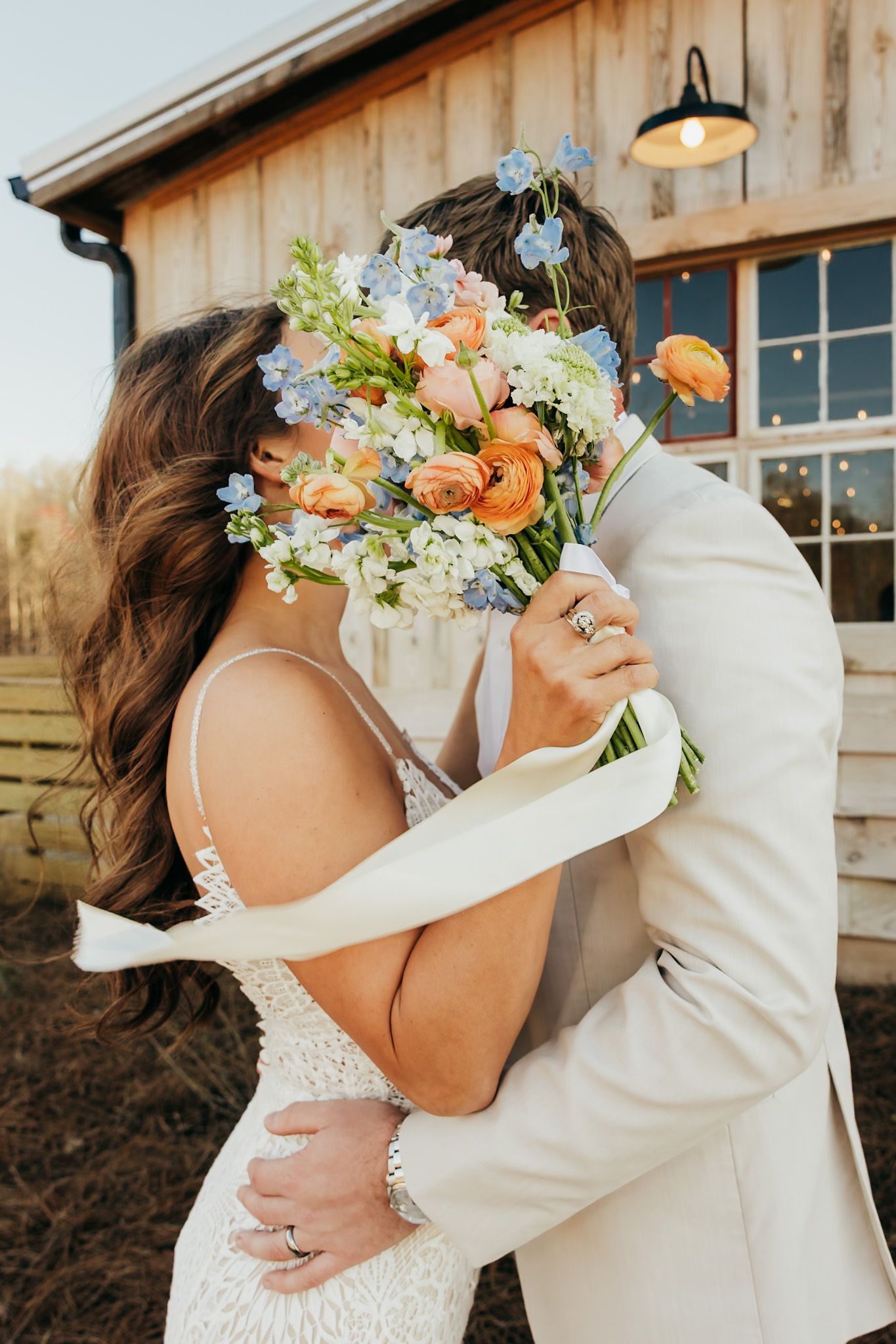 bride and groom kissing behind her spring bouquet