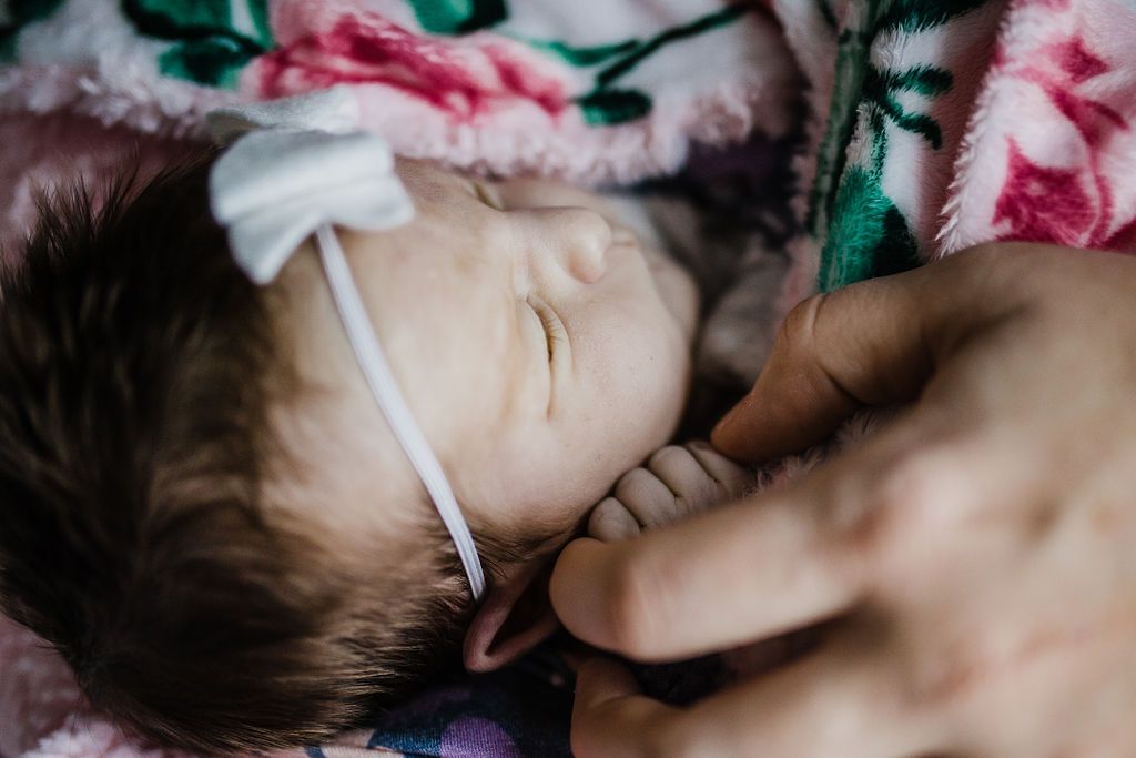 Close-up of sleeping newborn baby with floral blanket.