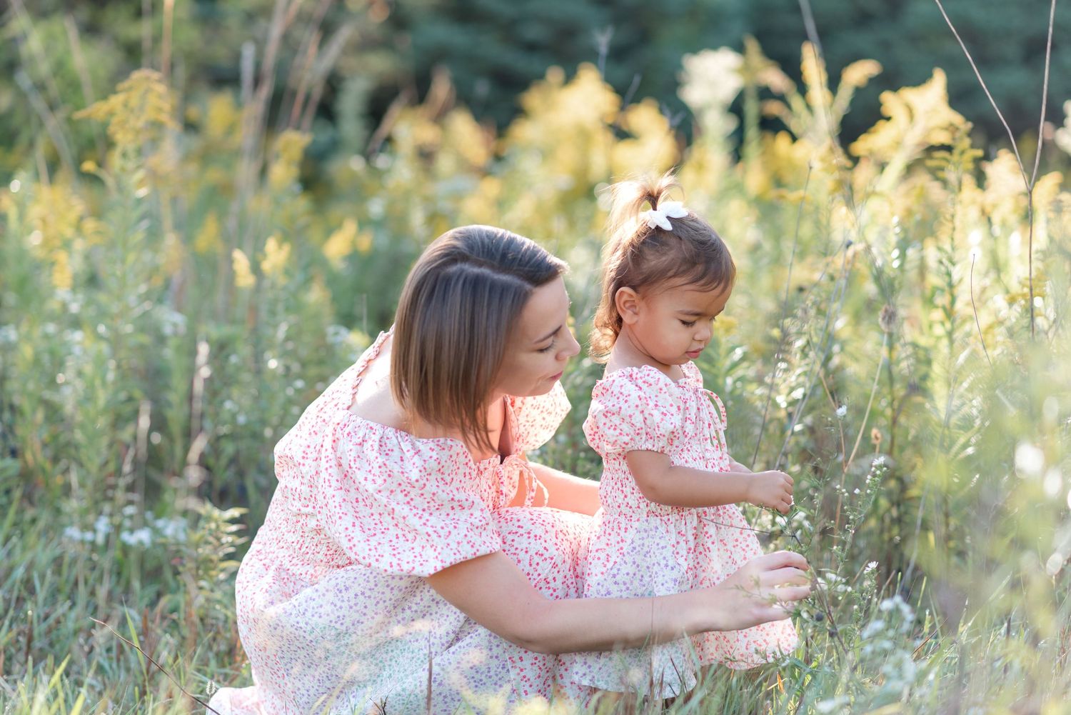 Normal, Illinois mother picking a flower for her daughter in a field of wildflowers during a mommy and me session by Julie Loy Photography
