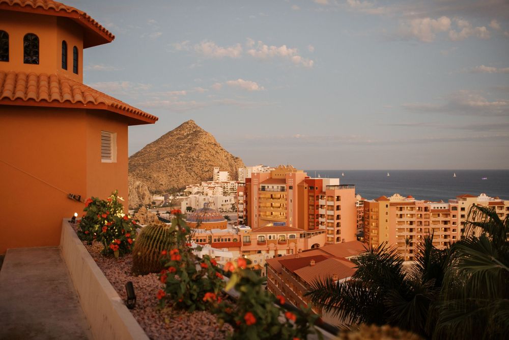 Panoramic view of coastal buildings with terracotta roofs and mountains against a sunset sky in Tenerife, Spain.