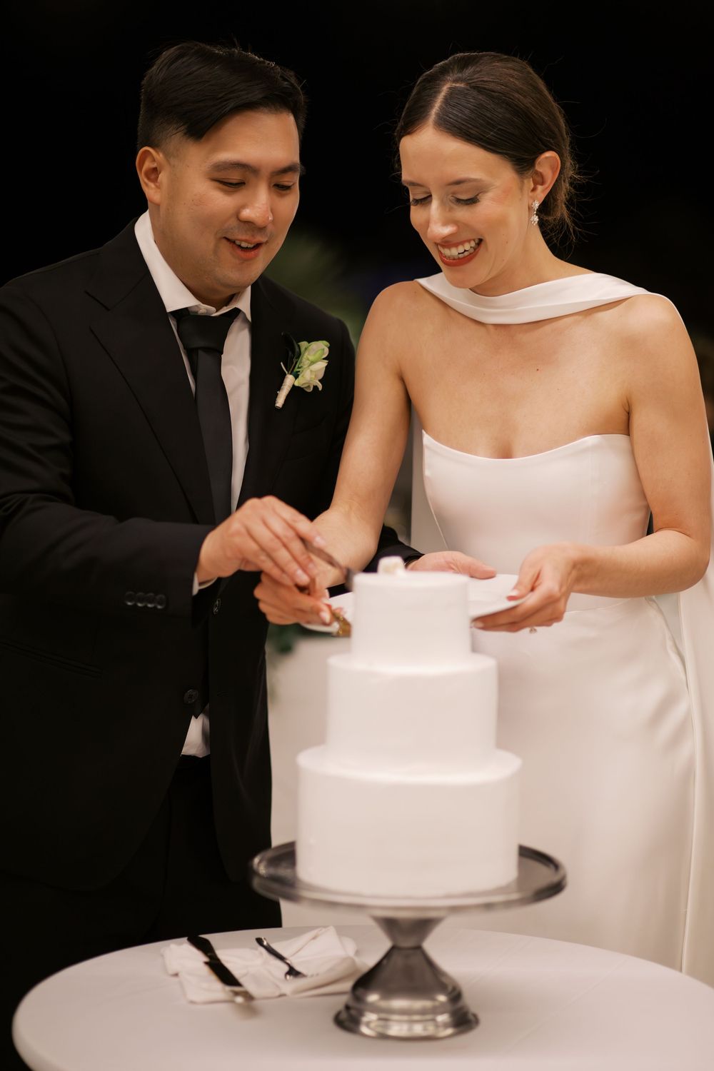 Couple cutting their elegant white wedding cake together at their reception.