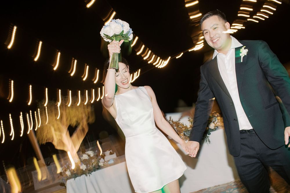 A couple in wedding attire dances together in a warmly lit venue with dramatic lighting and motion blur effects.