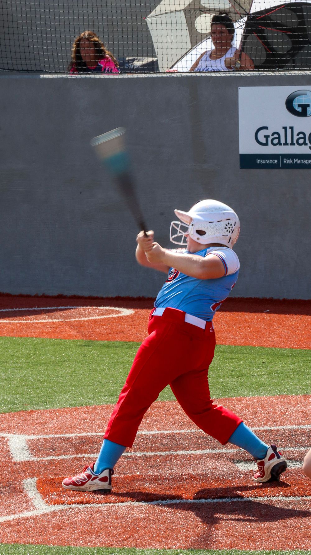 Baseball player in red pants and blue jersey demonstrates sliding technique on baseball field.