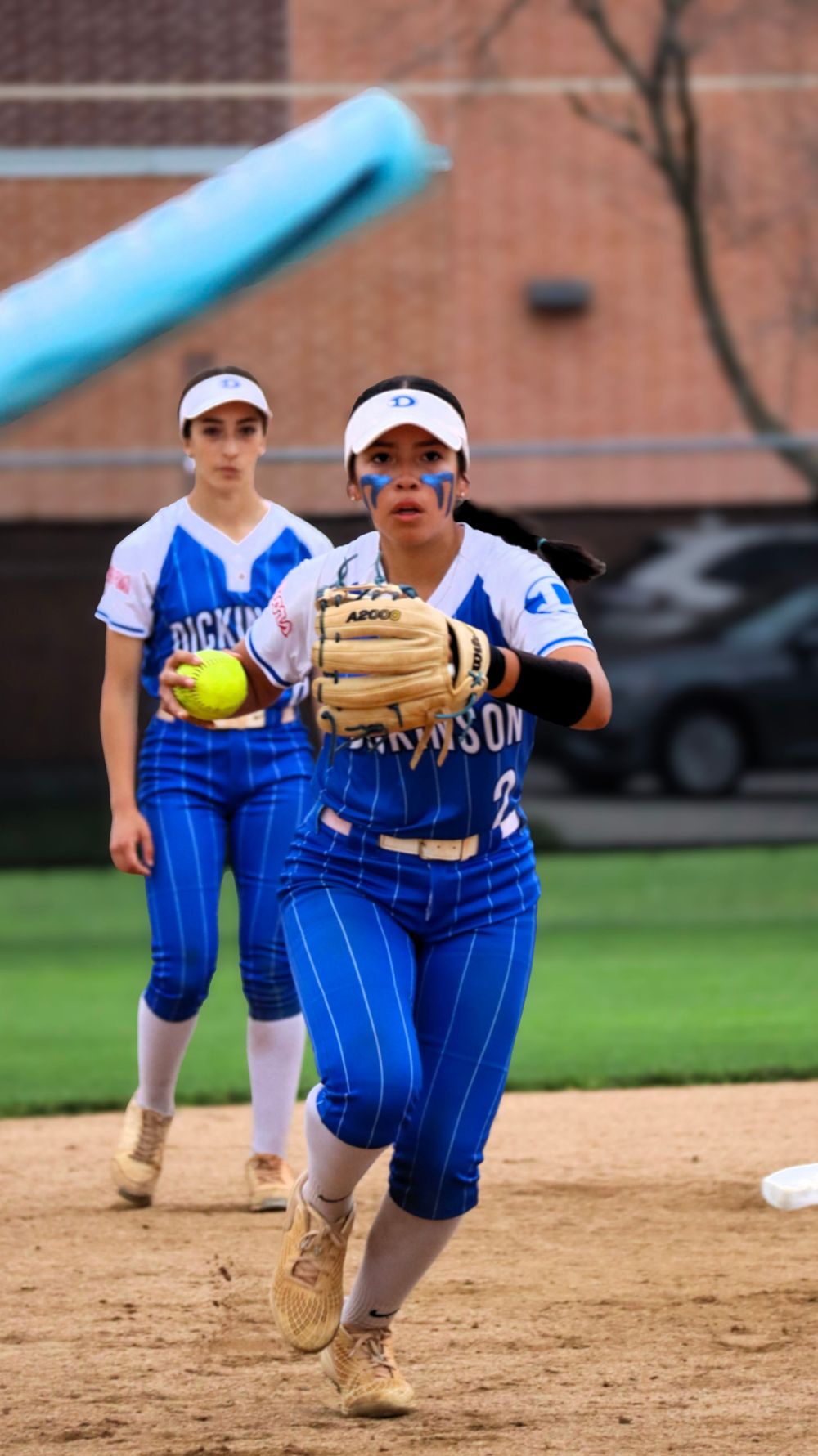 Softball player in blue uniform fielding ground ball during practice.
