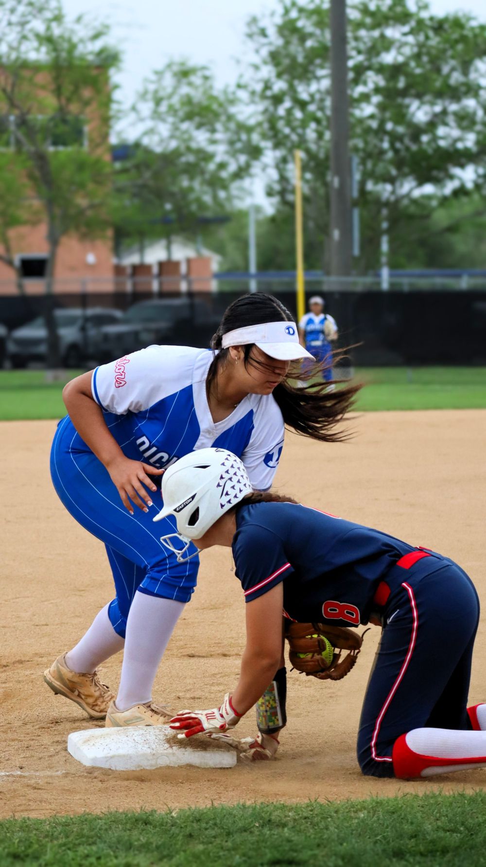 Action shot of softball players colliding at base during competitive play.