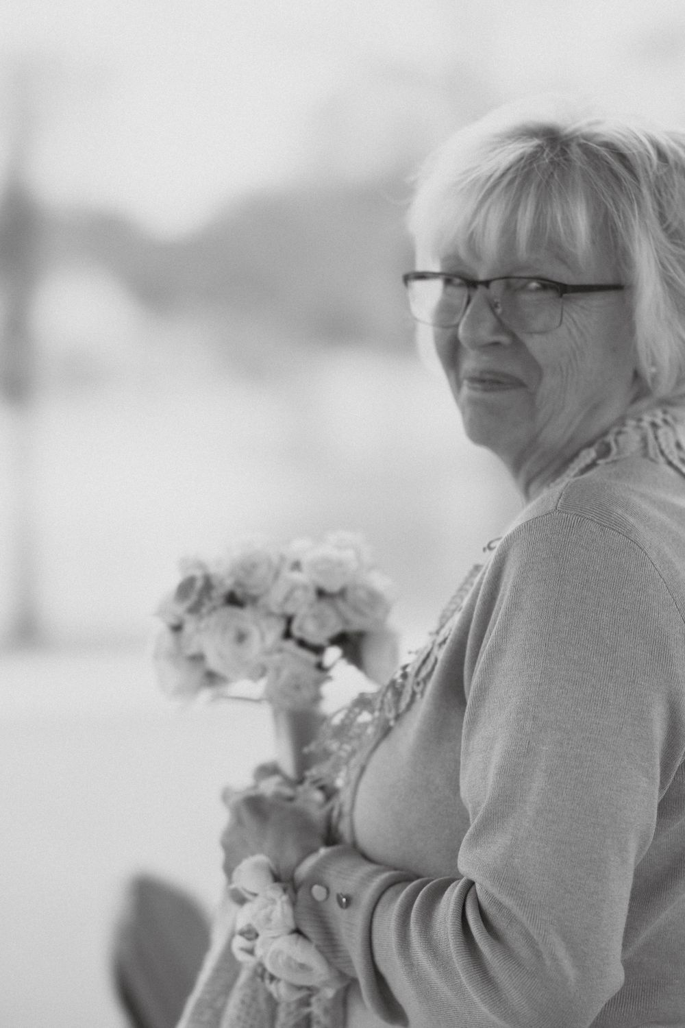 Black and white portrait of someone holding flowers while looking to the side.