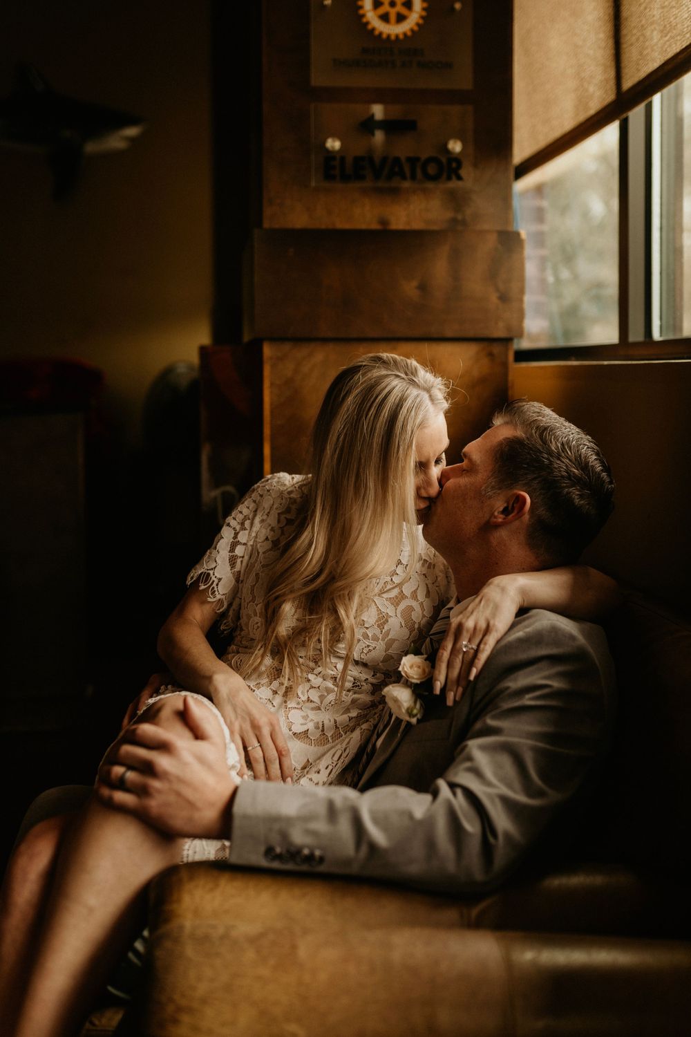 A romantic couple share an intimate moment in a dimly lit restaurant booth with vintage decor.