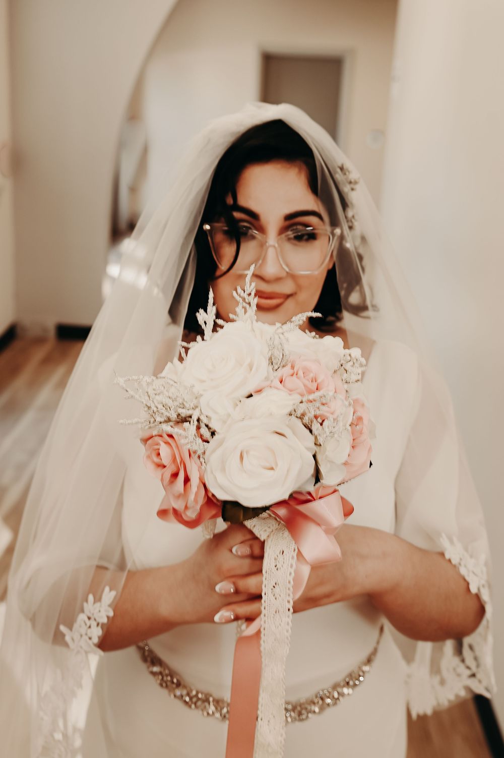 Close-up of bridal details showing lace veil and delicate pink and white floral accents.