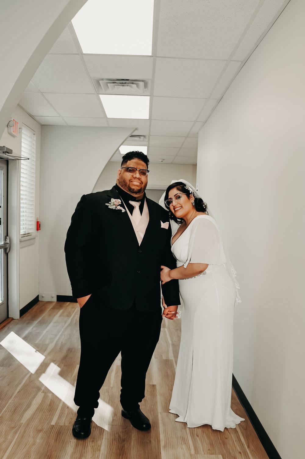 Wedding photo session in a bright indoor hallway with wooden floors.