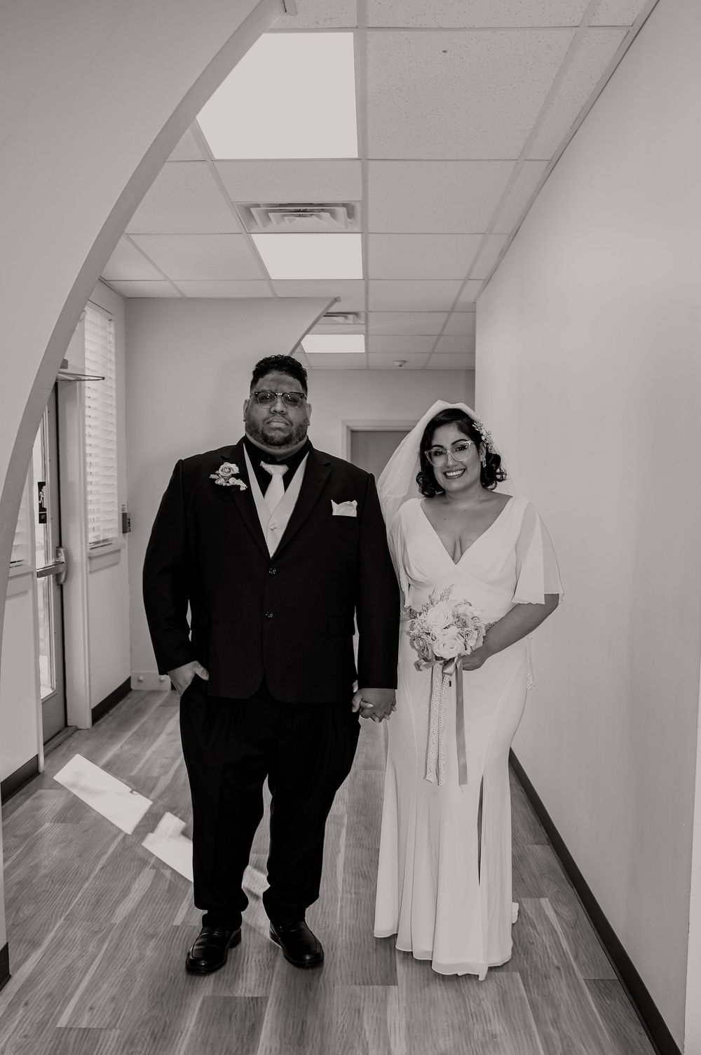 Couple poses together in a bright hallway during a wedding photoshoot.