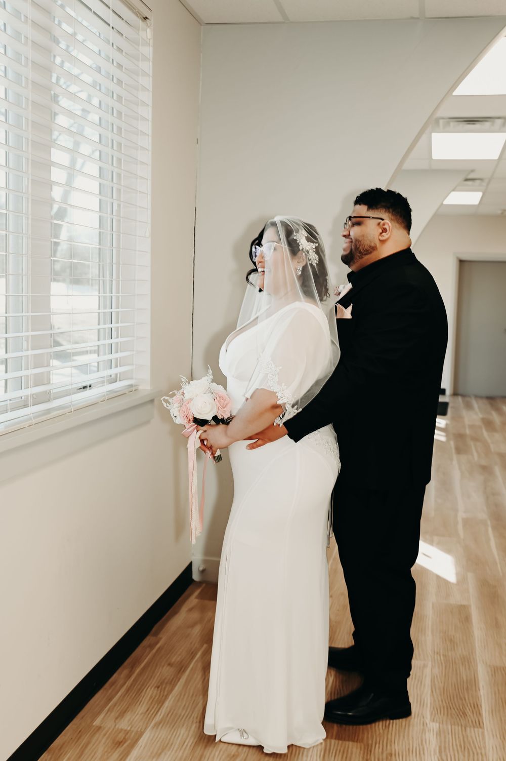 Wedding couple shares a moment in a sunlit hallway.