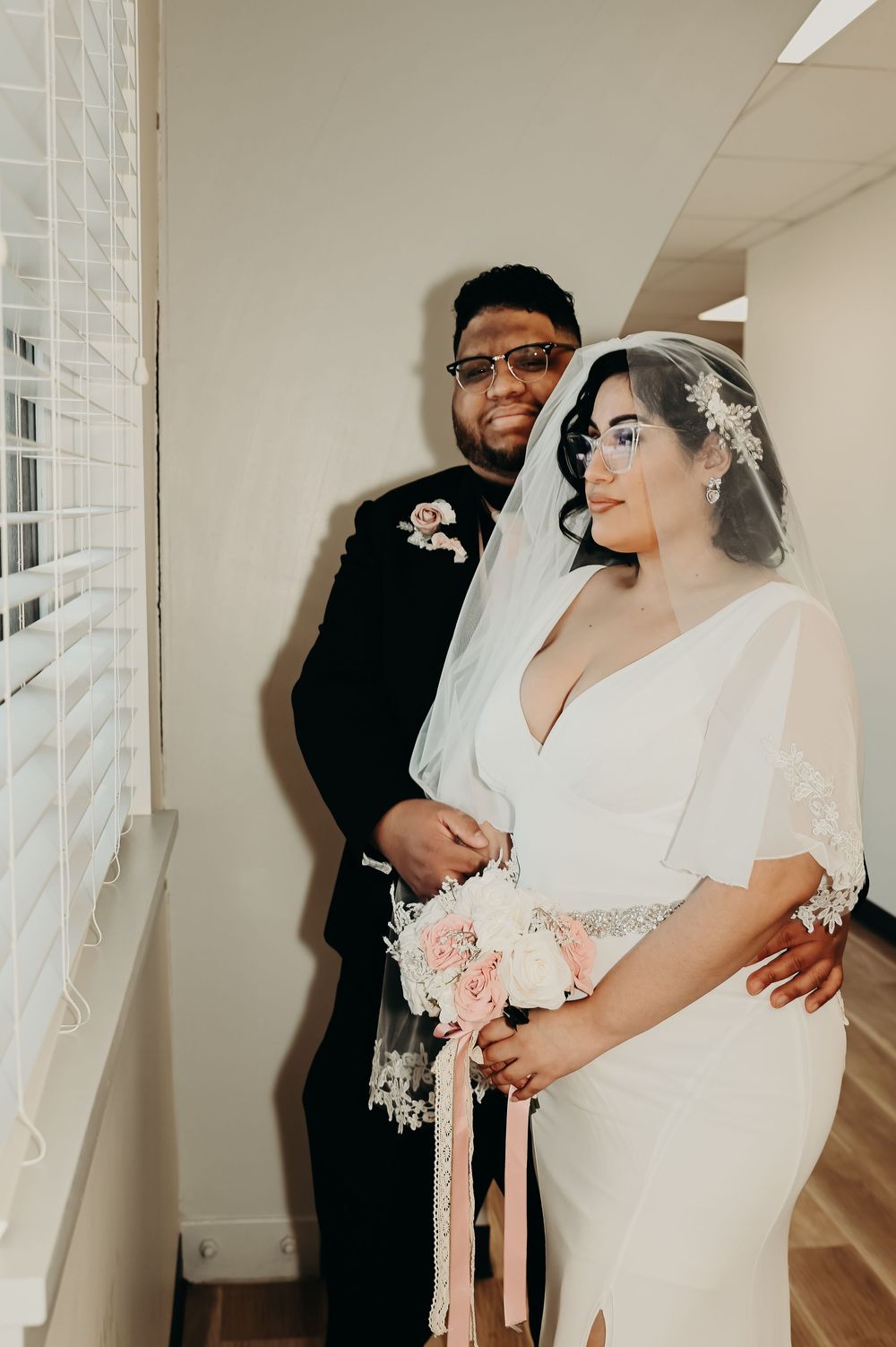 Wedding couple sharing an intimate moment in a sunlit hallway.